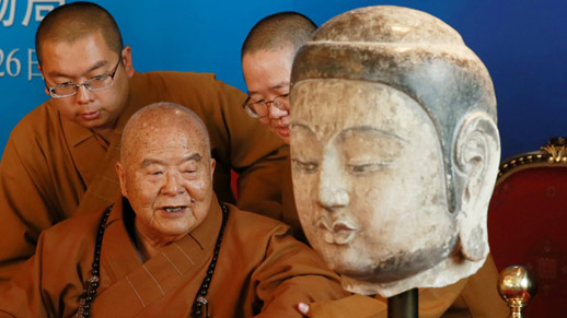 Buddha head with monks in background